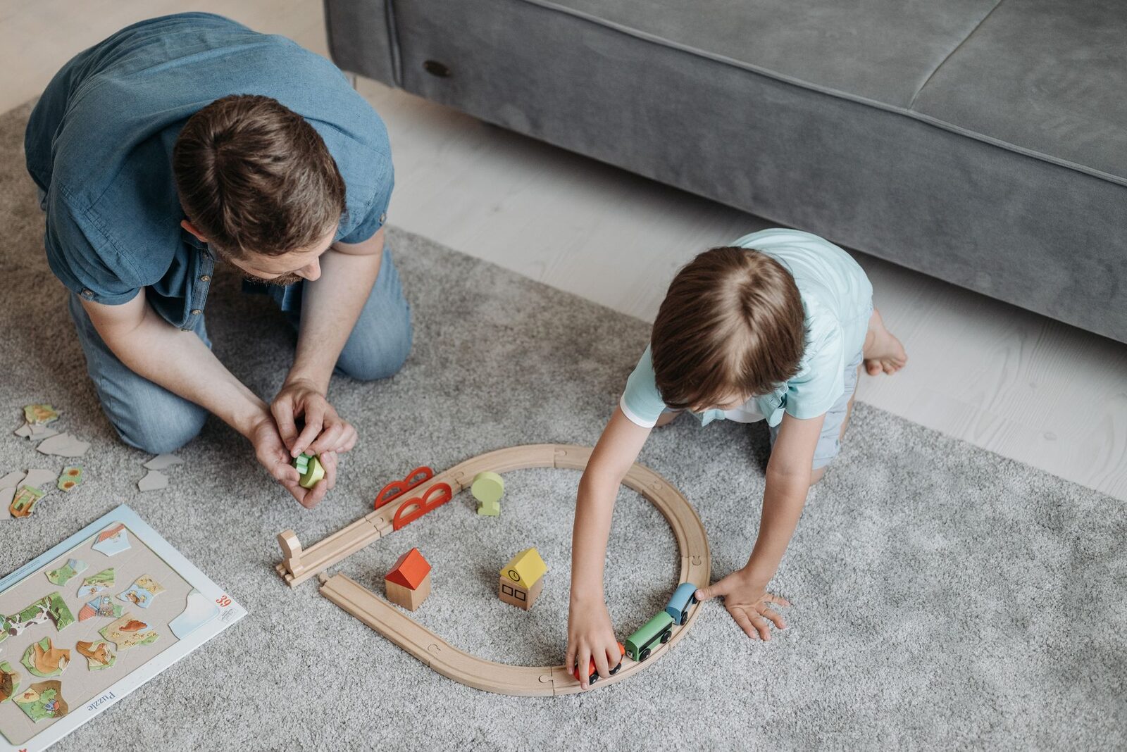 A parent and child building a wooden train track together